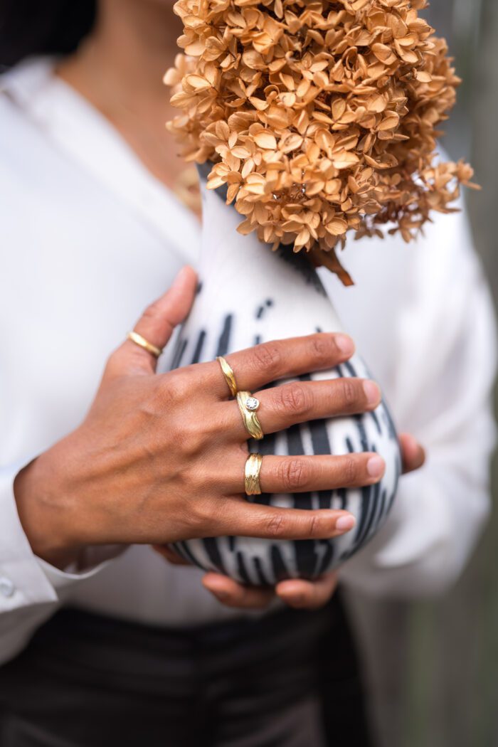 hand with eco gold rings holding a raku vase