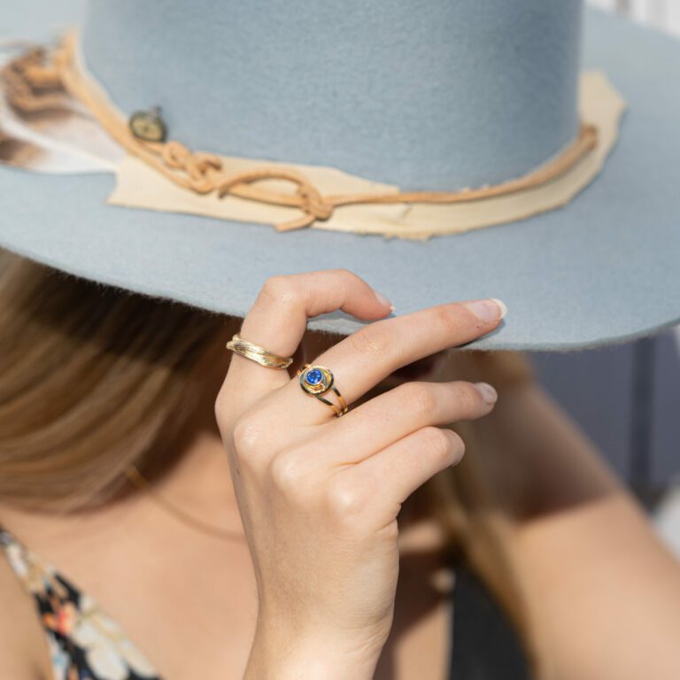 Dorothee Rosen 18k Yellow Gold ring with sapphire and 100% Fairmined Eco gold ring with hat in hand on model