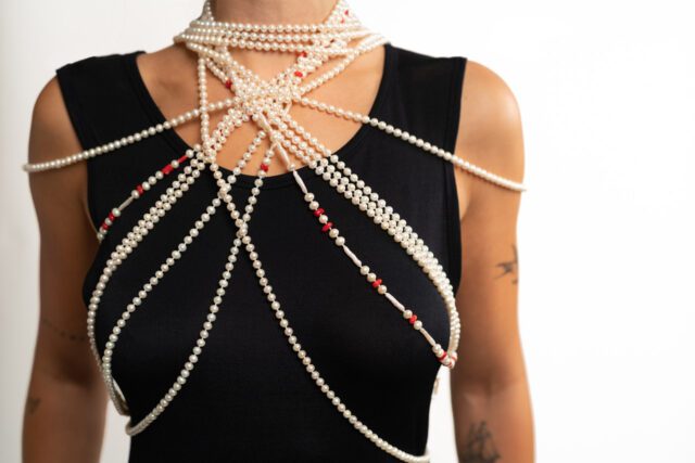 Model wearing 5 strands of pearls with coral accents